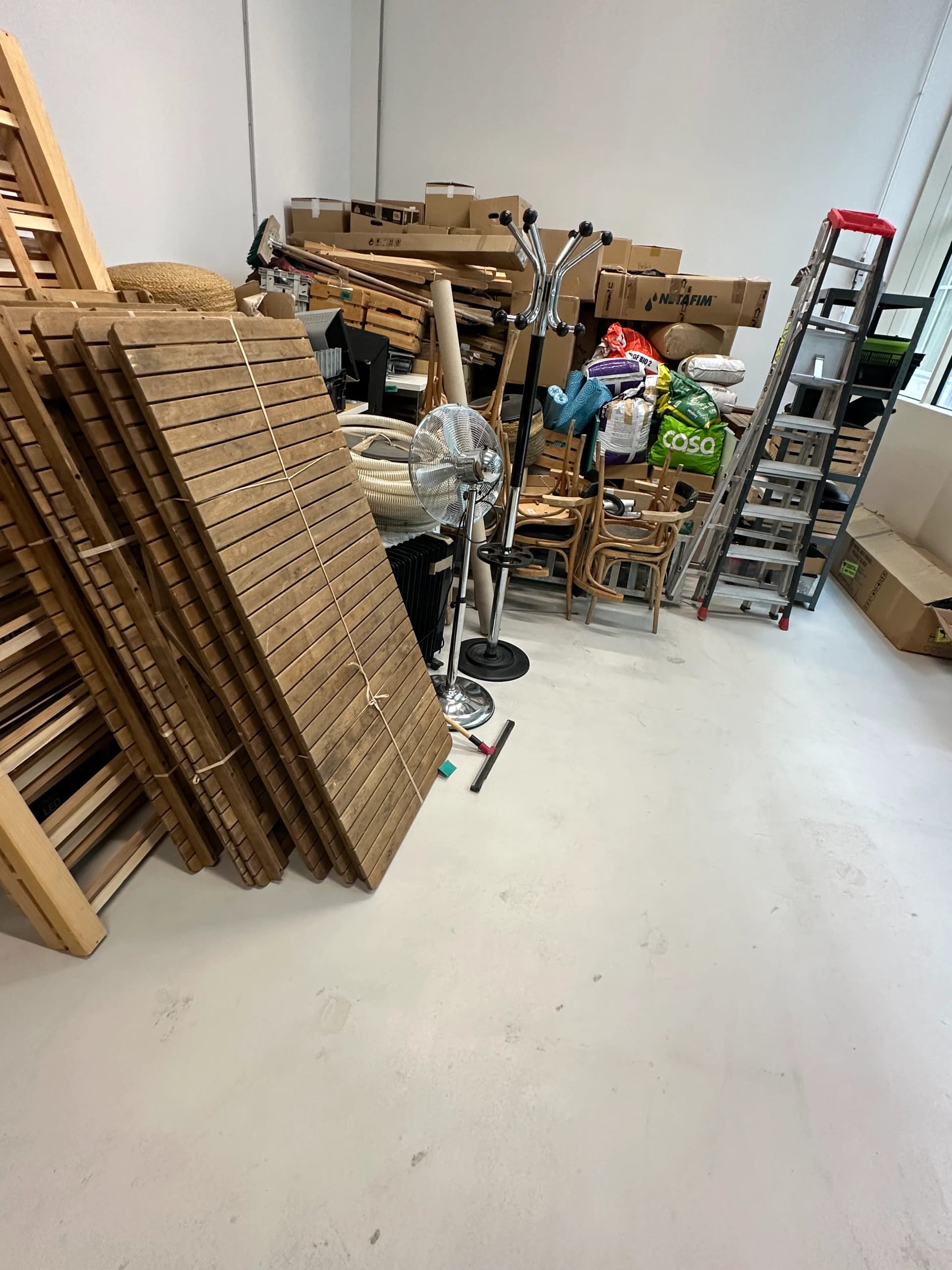 Débarras d'un local avec panneaux en bois et divers objets empilés