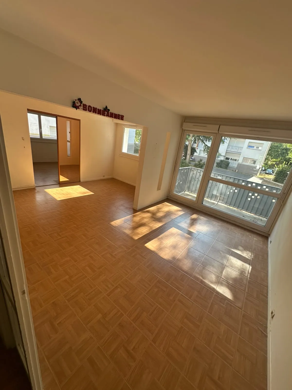 La même salle à manger vidée, baie vitrée et balcon dégagés après le débarras